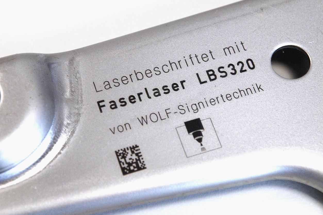 Laserbeschriftung auf Metall Mit Laserbeschrifter LBS320 beschriftetes Metallteil der Automobilindustrie (Beschriftung: Schrift, DataMatrix-Code, Logo)
